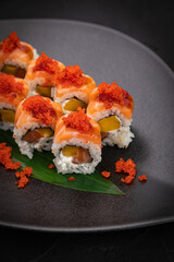 Japanese cuisine. Rolls on a black plate on a wooden table