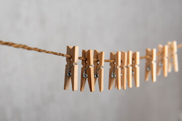 Wooden clothespins on rope on gray background. Laundry concept.