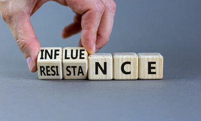 Influence or resistance symbol. Businessman turns cubes, changes the word 'resistance' to 'influence'. Beautiful grey background. Copy space. Business and influence or resistance concept.