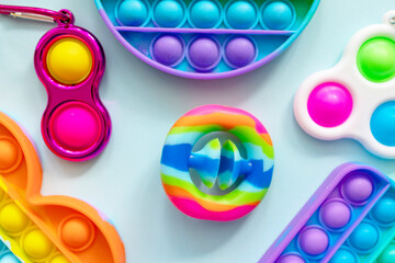 colorful antistress sensory toys fidget push pop it and trendy toy Snapperz on blue background - obrazy, fototapety, plakaty