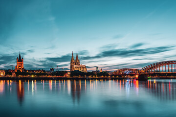 Fototapeta na wymiar Panoramic view of Cologne Cathedral with Hohenzollern Bridge at nightfall, Germany.