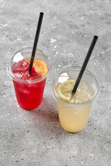 Colorful refreshment drinks lemonade in plastic glasses, outdoor stand with takeaway food