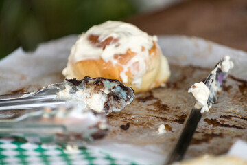 dessert bun with icing sugar top with tongs and knife in a pastry shop window