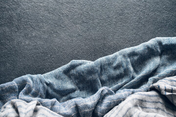 Abstract background with draped blue-gray cotton cloth, napkin, striped tablecloth or scarf on dark...