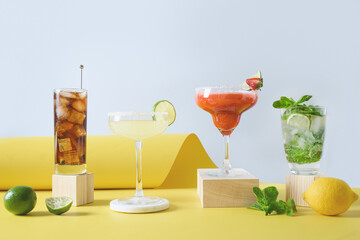 Freshness different cocktails mojito, cuba libre, margarita cocktail with lime, strawberries, and lemon on modern yellow background. Summer freshness beverage for festive party. Holiday aperitif.