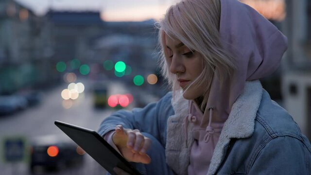 Girl With Tablet In Her Hands. Cute Young Girl With Pink Hair On The Background Of The Evening City.