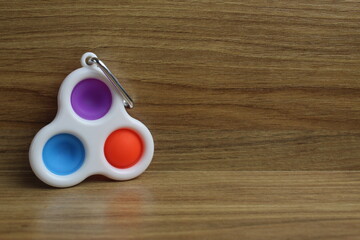 TOYs Popit SIMPLe DIMPLe A little spinner on a ri cell on a wooden background with a place for text...