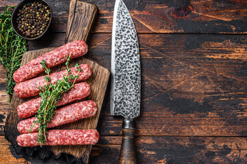 Homamade raw meat lula kebabs sausages on a cutting board. Dark wooden background. Top view. Copy...