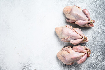 Raw quails on a kitchen table. White background. Top view. Copy space