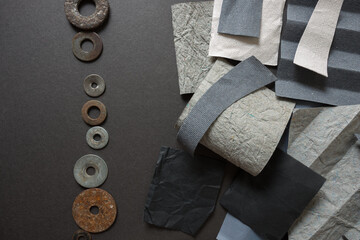 abstract composition with various shades of grey construction paper and old metallic and rusty washers - photographed from above in ambient light in a flat lay composition on dark grey