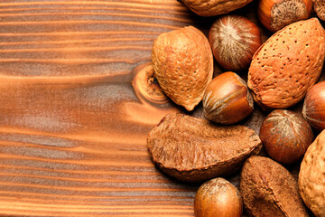 Almonds, walnuts and hazelnuts on a brown wooden background.