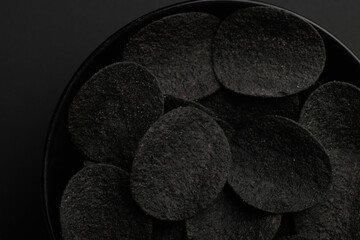Black chips and red hot peppers on black background