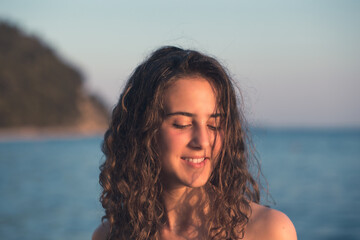 Beautiful, young teen girl with curly hair posing by the sea
