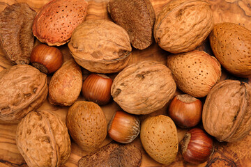 Almonds, walnuts and hazelnuts on a brown wooden background.