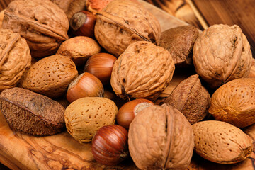 Almonds, walnuts and hazelnuts on a brown wooden background.