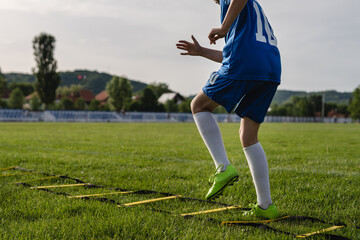 Close up on low section of unknown caucasian child boy training mobility and coordination on the football soccer field using ladder drills and exercise concept copy space - Powered by Adobe