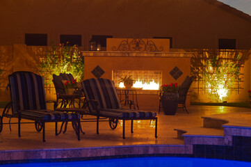 A night shot of a desert landscaped house in Mesa Arizona with an outdoor fireplace, pool and spa.
