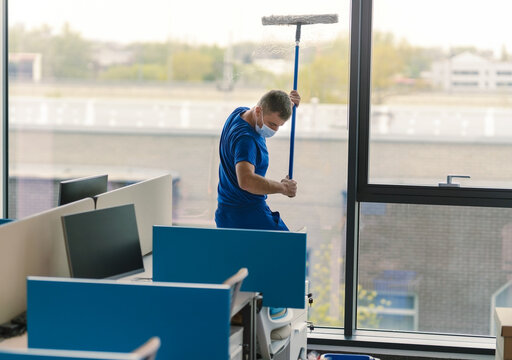 A professional window cleaner cleans an office window