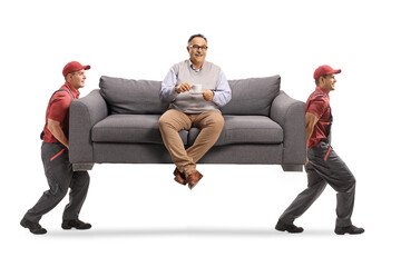 Movers carrying a couch with a mature man sitting and drinking coffee