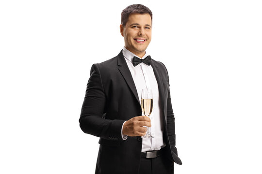 Young man in a suit and bow tie holding a glass of sparkling wine and looking at camera