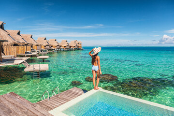 Travel luxury resort woman overwater bungalow hotel in Maldives. Luxury vacation hotel in Tahiti woman relaxing at infinity pool in French Polynesia travel summer holiday. - obrazy, fototapety, plakaty