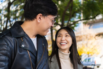 interracial couple, young multiracial asian american woman with her latin male partner in black leather jacket, smiling, hugging, outside