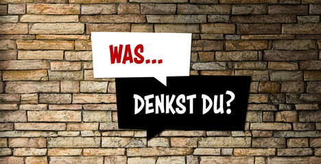 Fototapeta na wymiar speech bubbles with German message for WHAT DO YOU THINK? on a brick wall background