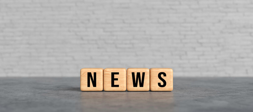 wooden cubes with the word NEWS in front of a white brick wall background