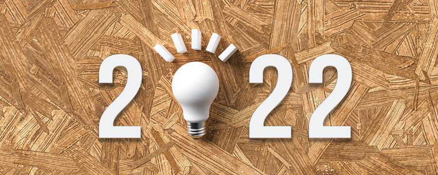 number 2022 with a lightbulb as a zero on particle board background