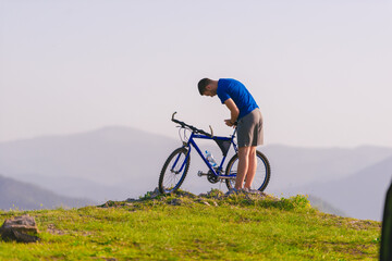 Fototapeta na wymiar Fit mountain biker riding his bike through green grass on top of a mountain.