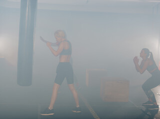 Side view portrait of a young woman doing boxing training with white smoke in the background