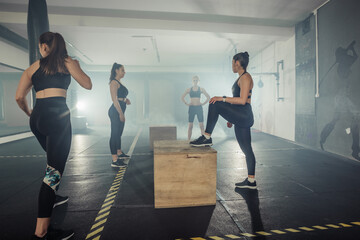 Four sportswomen are training glutes with multifunctional training in a sports club
