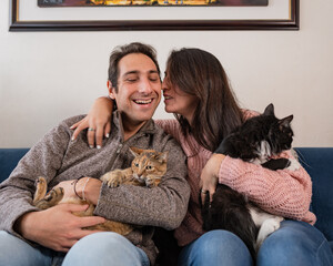 Beautiful couple having a good time with their cats at the living room 