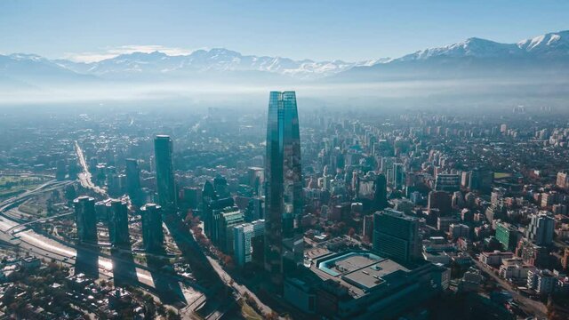 Aerial hyperlapse at Santiago de Chile on a sunny and dusty morning with the andean mountain range covered in snow