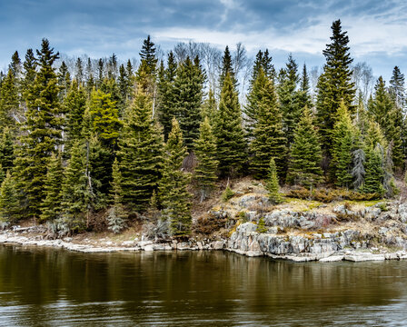 Image of the Grass river in northern Manitoba Canada, showing tall spruce trees and granite rock of the boreal forest. 