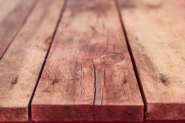 Horizontal old wooden table close up. Weathered red background with cracks.