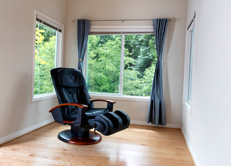 Home massage chair near large windows with view of trees