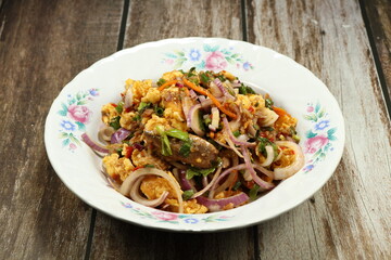 Traditional spicy salad mixed with herbal vegetable and seasoning with pickled fish sauce serving on the plate. 