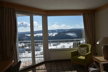 Fototapeta na wymiar Stunning view of snow covered landscape and cloudy sky from huge panoramic hotel window