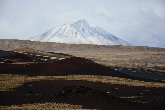 Vista de la reserva natural La Payunia con el volc&aacute;n Payun Matru cubierto con nieve de fondo, Mendoza, Argentina
