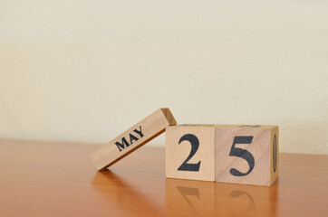 May 25, Date design with calendar cube on wooden table and white background.