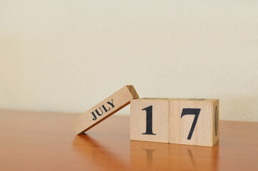 Naklejka premium July 17, Date design with calendar cube on wooden table and white background.