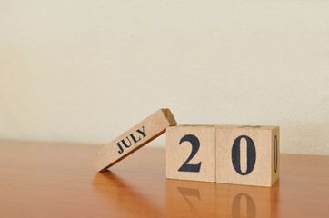 July 20, Date design with calendar cube on wooden table and white background.