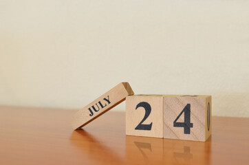 July 24, Date design with calendar cube on wooden table and white background.