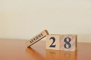 August 28, Date design with calendar cube on wooden table and white background.