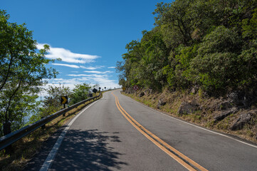 Estrada vazia e sinuosa no alto da montanha com placas de transito 