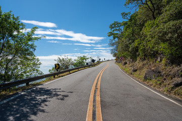Estrada vazia e sinuosa no alto da montanha com placas de transito 
