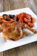 A view of a plate of roasted chicken quarters and ravioli.