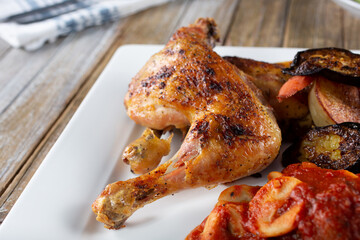 A view of a plate of roasted chicken quarters and ravioli.
