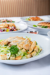 A view of several salad plates, featuring chicken Caesar.
